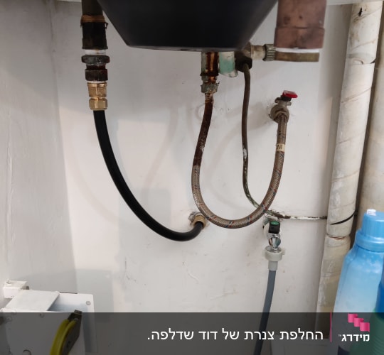 צינורות מתכת וגומי מתחת לכיור עם ברזים